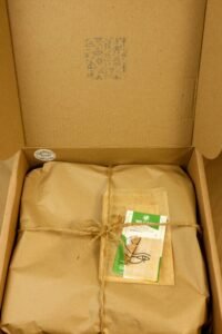 Sustainable packaging with brown paper and twine inside a cardboard box.