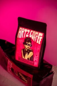 Close-up of Artz Coffee packaging on a vibrant pink background, showcasing artistic design.