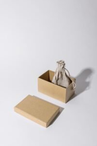 A minimalist kraft cardboard box with a linen pouch inside, under neutral lighting.